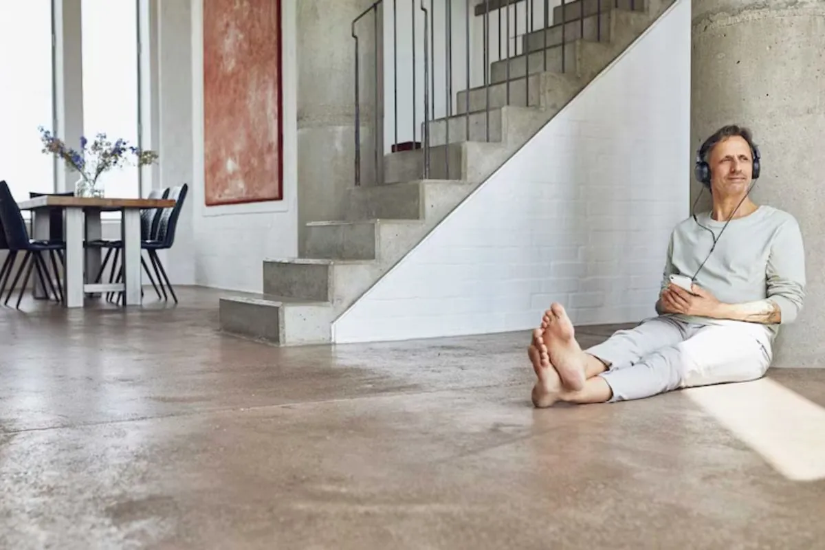 man sitting on concrete floors while listening music